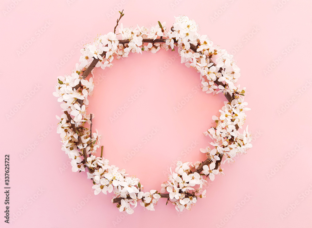 Spring wreath of flowers, blooming tree branches, leaves in a circle on a pastel pink background. Advertising content for Birthday, Valentines Day, Womens day. Flat lay, top view, close up, copy space