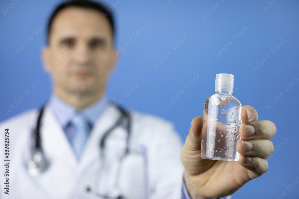 Doctor in lab coat and stethoscope with sanitizer alcohol gel dispenser in hand to prevent spread of covid-19 coronavirus. Focus on antiseptic. Personal hygiene, care, distancing, protection concept Doctor in lab coat and stethoscope with sanitizer alcohol gel dispenser in hand to prevent spread of covid-19 coronavirus. Focus on antiseptic. Personal hygiene, care, distancing, protection concept