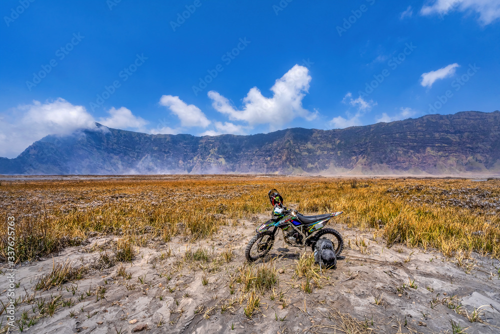 Travel concept of a journey to Bromo mountain in Indonesia - well knowd for landscape beauty and active volcanoes. An Asian male tourist standing relax on the view point Travel concept of a journey to Bromo mountain in Indonesia - well knowd for landscape beauty and active volcanoes. An Asian male tourist standing relax on the view point