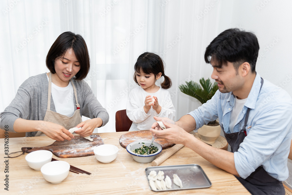 Young Asian mom and dad making dumplings with daughter Young Asian mom and dad making dumplings with daughter
