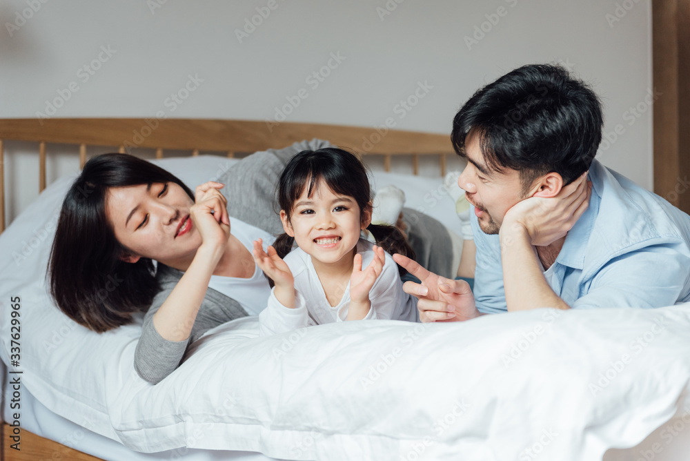 Young Asian father and mother are playing with their daughter on the bed Young Asian father and mother are playing with their daughter on the bed