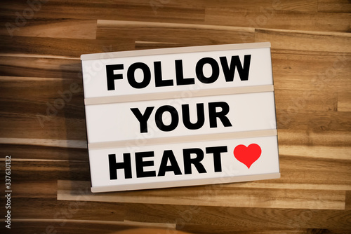 Lightbox or light box with message Follow your heart on a wooden table background
