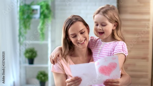 Pretty little girl congratulates mom to mothers day with greeting card. Medium shot on RED camera photo