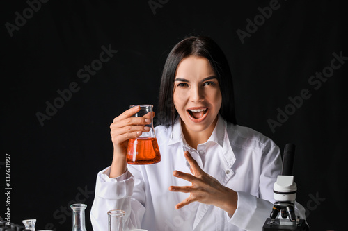 Crazy female alchemist with potion on dark background