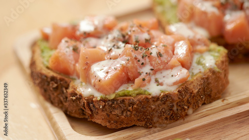 Salmon, avocado paste and white sauce on slice of baguette