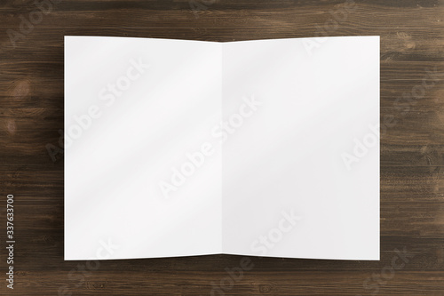 Blank opened bi-fold flyer brochure cover with soft overlay shadow on wooden background as template for design presentation, invitation card, etc.