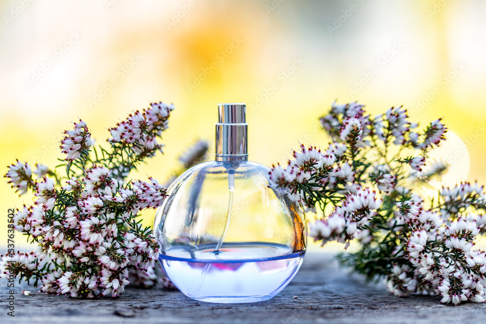 Light blue perfume bottle with flowers on bokeh background. Perfumery, cosmetics, fragrance collection. Light blue perfume bottle with flowers on bokeh background. Perfumery, cosmetics, fragrance collection.