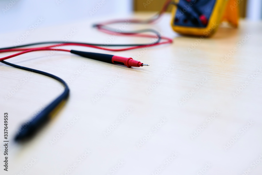 The multimeter is yellow, and red wires and black wires are placed on