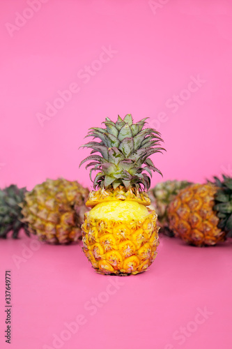 three whole pineapples with pink backdrop