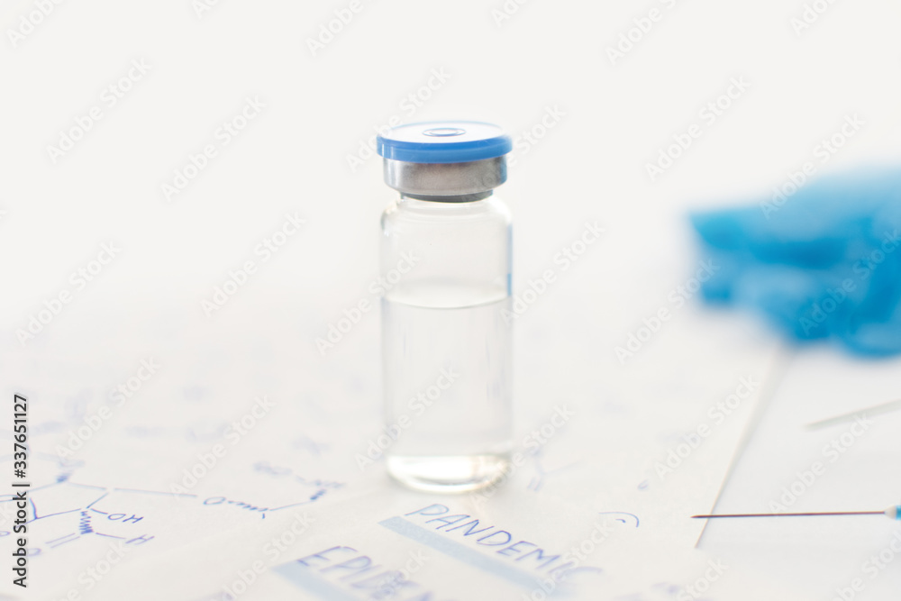 Medicine bottle, blue rubber gloves, syringes, papers with handwritten formulas and pandemic inscription on light background. Coronavirus vaccine development. 2019-nCoV liquid antidote. Copy space. Medicine bottle, blue rubber gloves, syringes, papers with handwritten formulas and pandemic inscription on light background. Coronavirus vaccine development. 2019-nCoV liquid antidote. Copy space.