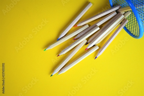 Fallen colored pencils on yellow background