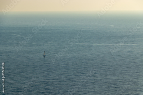 aerial view of a single Sailing boat in open blue sea from the viewpoint cap andritxol, mallorca, Spain © Martin