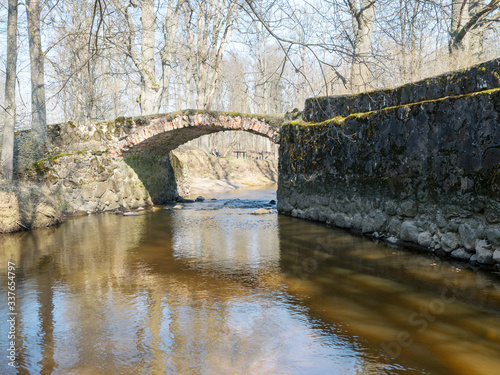 The Masonry  bridge over the river of Cuja, a sunny day in early spring with clear blue skies, the banks of a small river photo