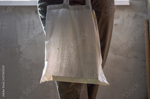 Female hands hold an eco bag. Zero waste. Sustainable lifestyle concept.
Woman holding textile glocery, reusable shopping bag, she wears green cotton pants photo