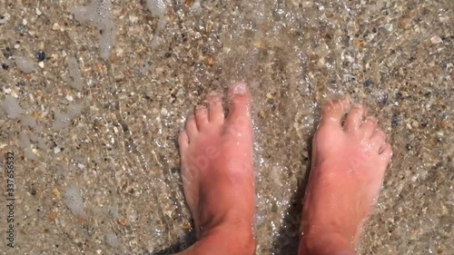 Black Sea waves washing man's feet at the sandy beach