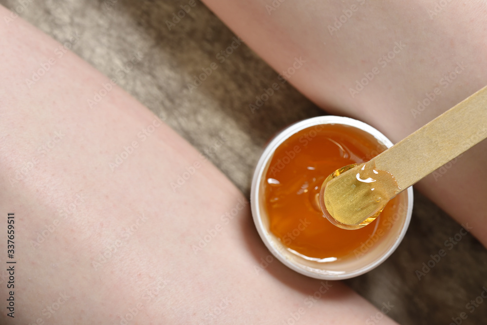 Sugar paste in a jar between the legs of a woman. Depilation Sugaring. Beauty and skin care concept.