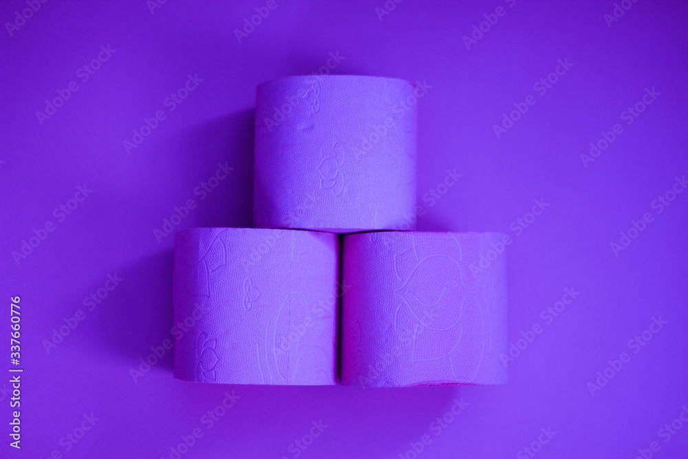 Several rolls of toilet paper isolated on lush purple background. A supply of toilet paper in case of a pandemic. COVID-19 coronavirus outbreak concept. Shortage due to buying panic. Сopy space. Several rolls of toilet paper isolated on lush purple background. A supply of toilet paper in case of a pandemic. COVID-19 coronavirus outbreak concept. Shortage due to buying panic. Сopy space.