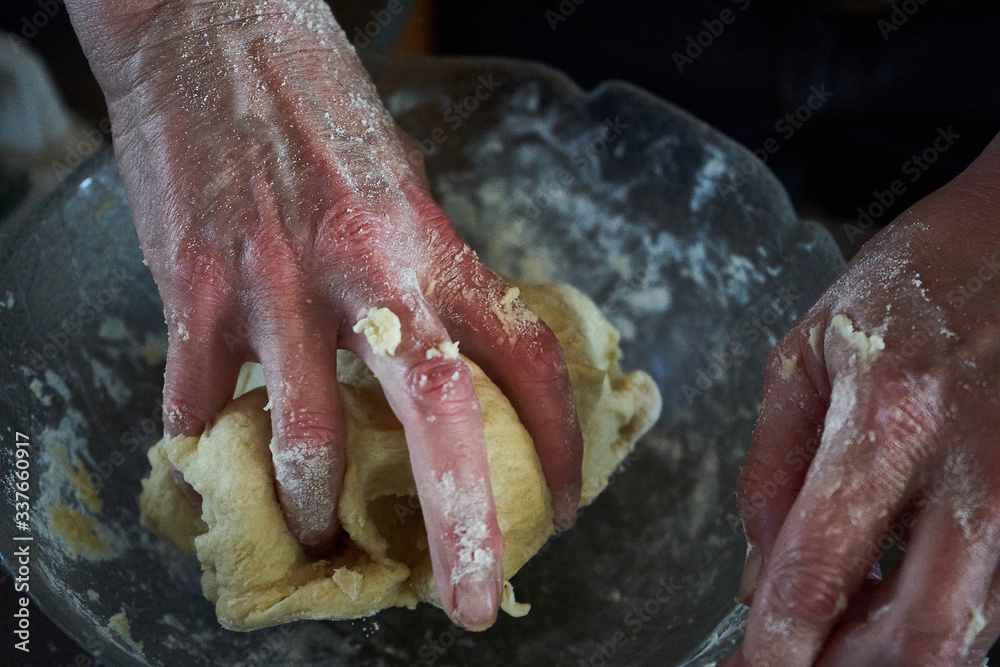 woman making bread with their hands in the kitchen on a dark backround. 