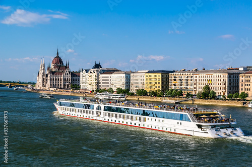 Photography A luxury river boat,  sails past the inpressive Hungarian House of Parliament on the Danube River