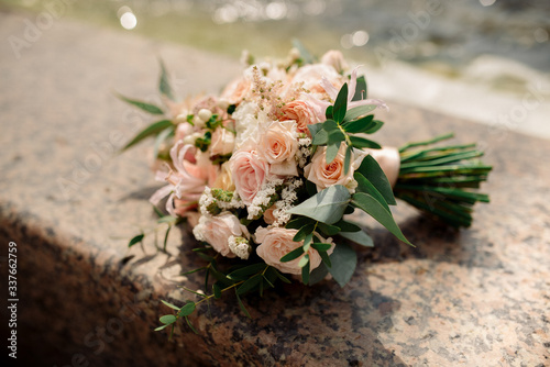 Bridal bouquet of roses, eustoma and ornamental plants on a stone background
