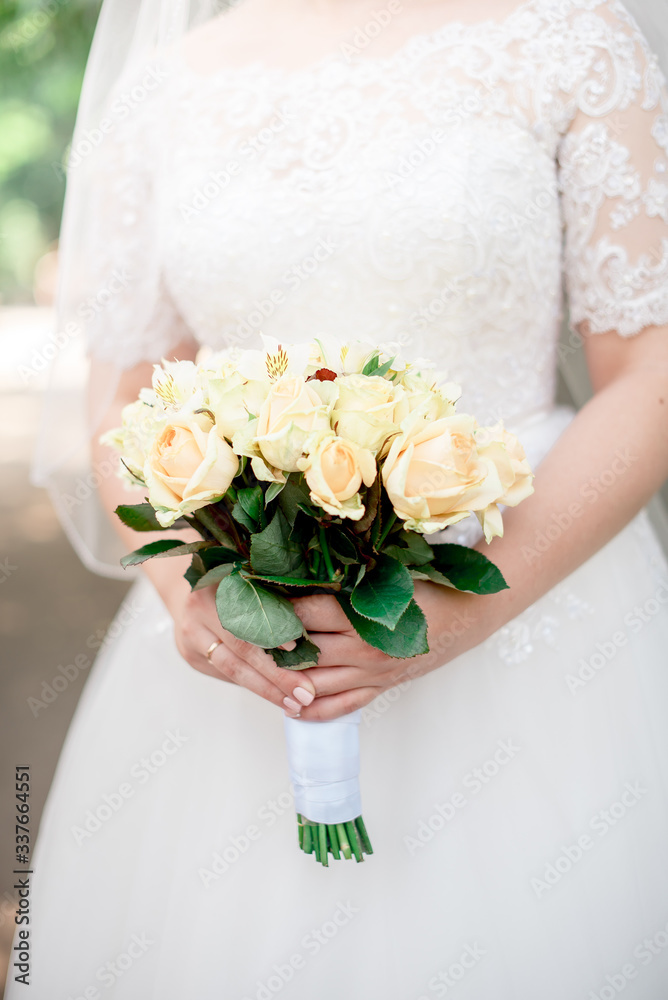 Bouquet of roses, ranunculus in the hands of the bride at a wedding ceremony
Bouquet of roses, ranunculus in the hands of the bride at a wedding ceremony