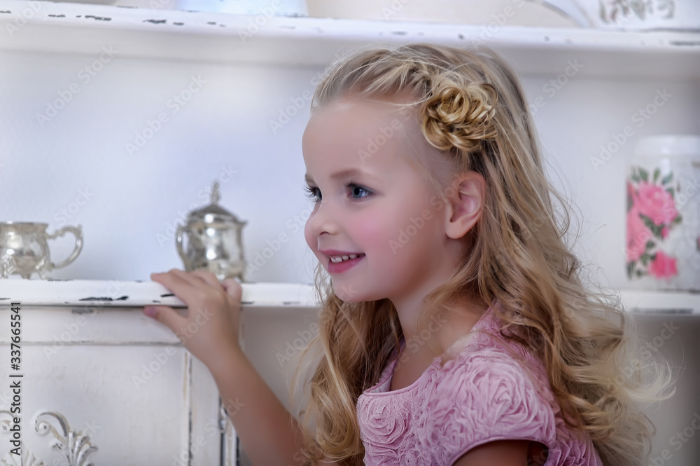 little blonde girl in a pink dress with curls and a beautiful hairstyle ...