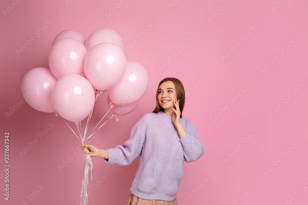 Smiling cute girl posing with pastel pink air balloons isolated over pink background. Beautiful happy young woman on a birthday holiday. space for text Smiling cute girl posing with pastel pink air balloons isolated over pink background. Beautiful happy young woman on a birthday holiday. space for text