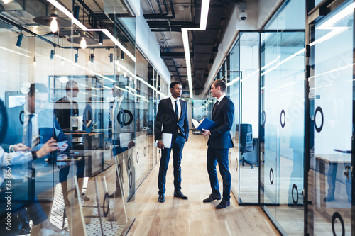 Diverse business people having discussion in modern office corridor