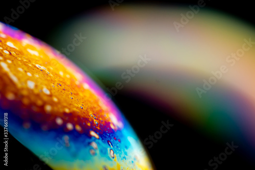 Psychedelic abstract planet from soap bubble, Light refraction on a soap bubble, Macro Close Up in soap bubble. Rainbow colors on a black background. Model of Space or planets universe cosmic galaxy.