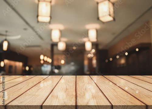 Wooden top table with bokeh light effect and blur restaurant on background, blur background © DEEP PIXEL