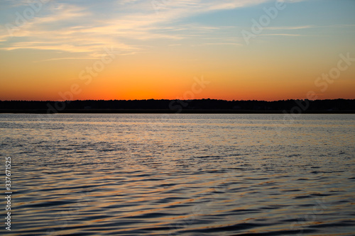 Beautiful landscape view with river slowly flowing with small waves during the sunset. © Artūrs Stiebriņš