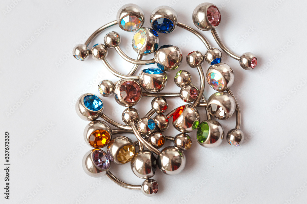 A mix of different multicolored navel piercing earrings - red, orange, yellow, green, blue, indigo blue and purple. Macro closeup A mix of different multicolored navel piercing earrings - red, orange, yellow, green, blue, indigo blue and purple. Macro closeup