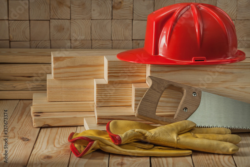 construction carpentry tools red helmet glaves and handsaw on wooden background photo