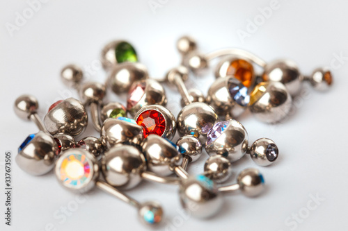 A mix of different multicolored navel piercing earrings - red, orange, yellow, green, blue, indigo blue and purple. Macro closeup
