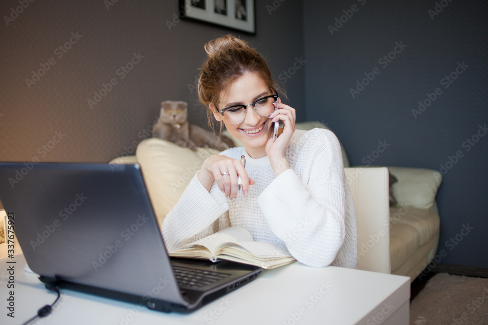 Freelance and remote work. Workplace in a home environment, a young attractive woman sitting with a laptop Freelance and remote work. Workplace in a home environment, a young attractive woman sitting with a laptop