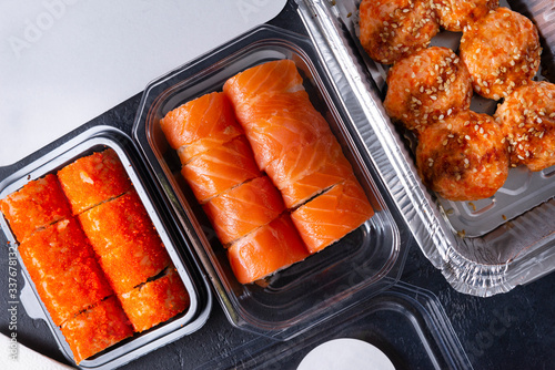 set of rolls Philadelphia rolls with salmon, California rolls with caviar, baked with cheese, sushi with delivery in containers, Japanese food on a black background, top view,