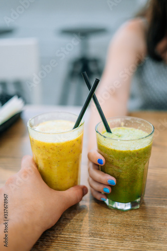 Glasses with vegetable and fruit smoothie. Man and woman holding glasses with spinach and smoothie