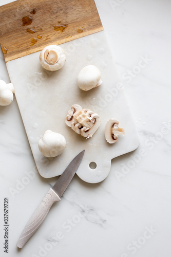 Fresh sliced champignon mushrooms on cutting board.