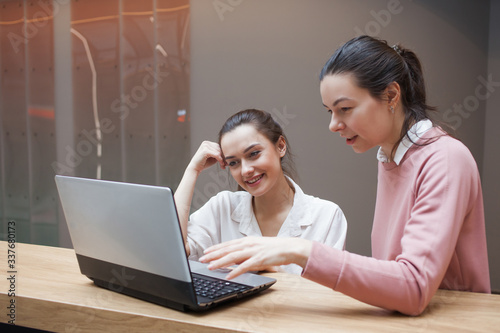 Two young women at work are engaged in discussing a work project. photo