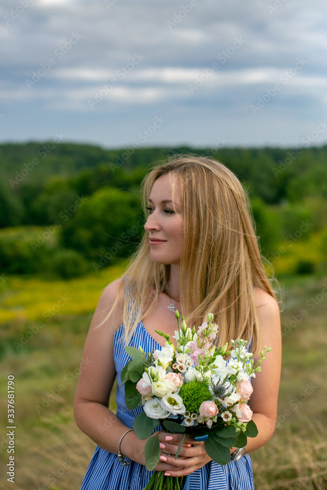 vertical close-up portrait of a beautiful thirty-five year old blonde with a bouquet against the backdrop of a summer landscape vertical close-up portrait of a beautiful thirty-five year old blonde with a bouquet against the backdrop of a summer landscape