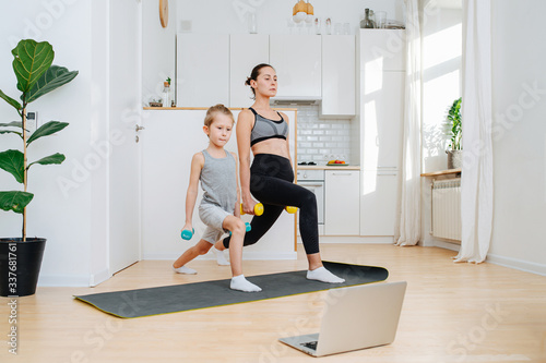 Family online training with dumbbells against the background of white kitchen