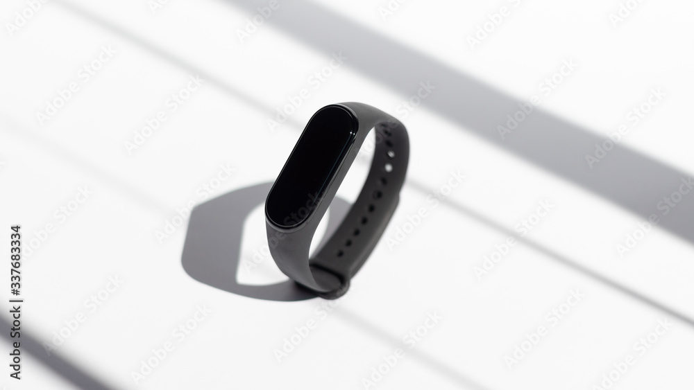 Smart activity fitness tracker on a white background the rays of the morning sun. Sport bracelet. Black fitness watch. Smart activity fitness tracker on a white background the rays of the morning sun. Sport bracelet. Black fitness watch.