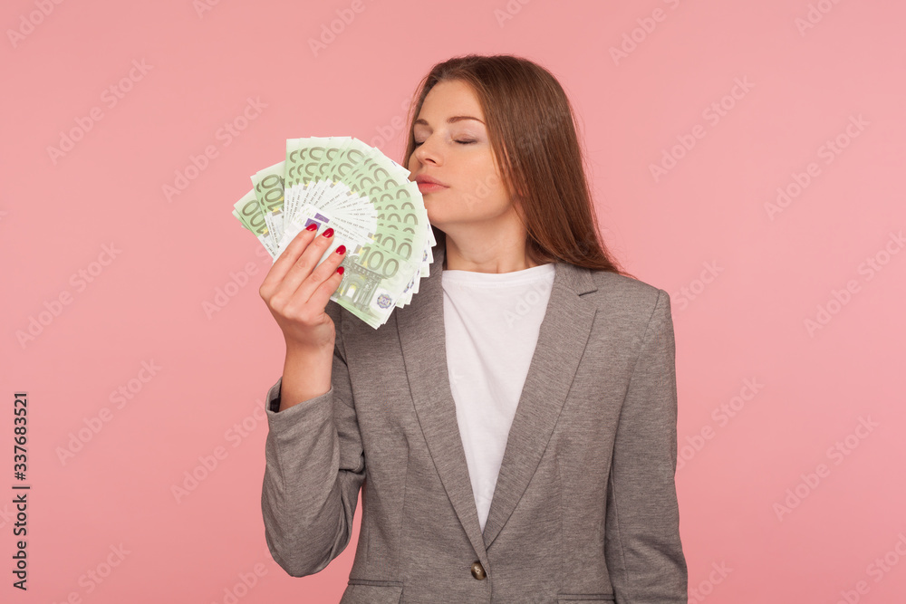 Greedy for money. Avaricious businesswoman in suit jacket smelling euro banknotes with expression of pleasure, enjoying financial success, wealthy life. indoor studio shot isolated on pink background Greedy for money. Avaricious businesswoman in suit jacket smelling euro banknotes with expression of pleasure, enjoying financial success, wealthy life. indoor studio shot isolated on pink background