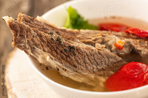 Shorpo in a white plate with a piece of beef meat in a broth with vegetables close up photo