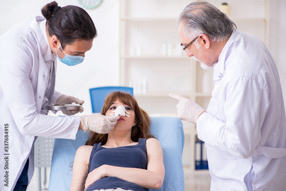 Two male doctors and young woman in plastic surgery concept Two male doctors and young woman in plastic surgery concept