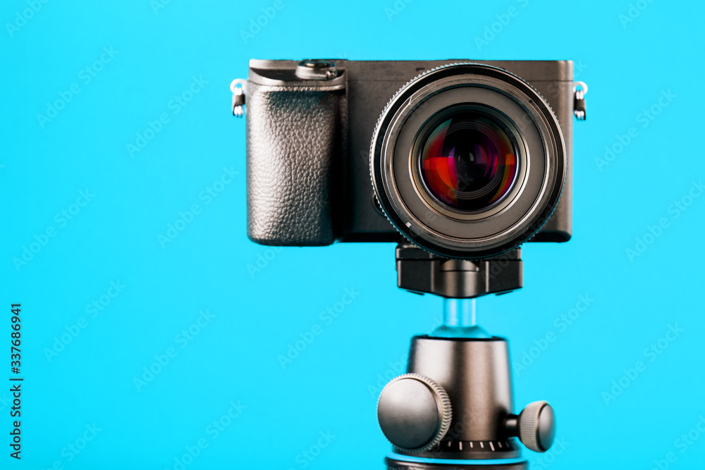 Camera on a tripod, on a blue background. Record videos and photos for your blog or report.