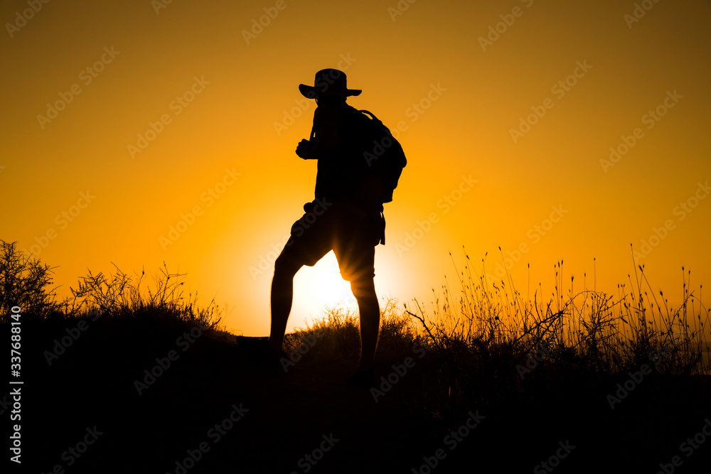 Silhouette of a womanwith a backpack in thesunset.