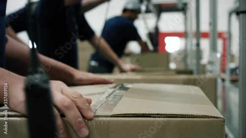 An operator closes a cardboard box with adhesive tape in a warehouse, after filled it with products. The operator puts tape on the cardboard box in the packaging line.Automation shipping logistics