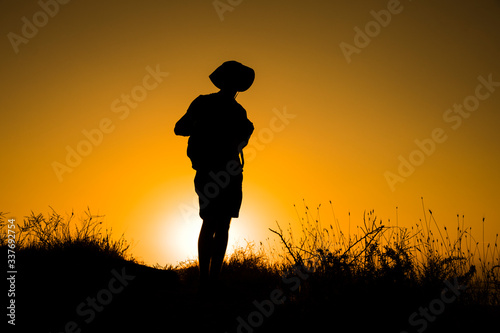 Silhouette of a womanwith a backpack in thesunset.