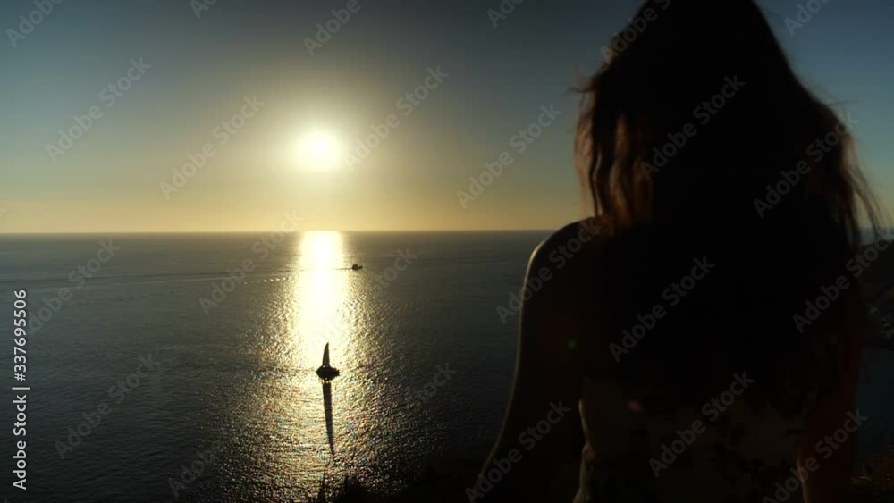 woman silhouette stands on beach edge and admires pictorial sunset reflection in water with yacht slow motion backside view woman silhouette stands on beach edge and admires pictorial sunset reflection in water with yacht slow motion backside view